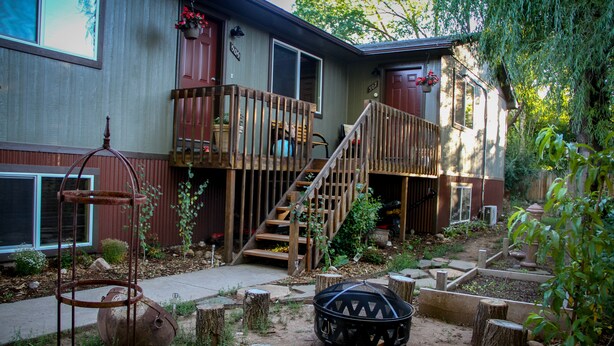 A house with a wooden deck, a staircase, and a garden with raised beds and a fire pit. - The 8th Street Retreat Looks Booked it may not be Call Us (Carbondale)