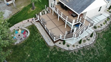 Relax on the spacious deck with a covered seating area, surrounded by a well-maintained lawn and stone pathway.