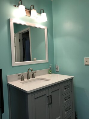 Een bad/douchecombinatie, een haardroger, handdoeken, zeep