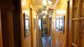 A wooden hallway with doors and windows, a ceiling fan, and a light fixture.