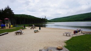A lakeside park with picnic tables, chairs, and a playground.