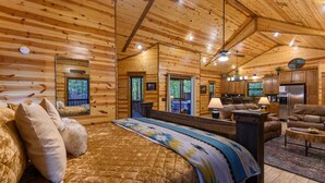 Ein Blockhaus-Interieur mit einem großen Bett, einer Couch, einem Essbereich und einer Küche.