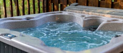 Un jacuzzi con una terraza de madera y una valla de madera al fondo.