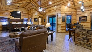 Ein Holzblockhaus-Innenraum mit Ledersofa, Holzesstisch und Kamin aus Stein.