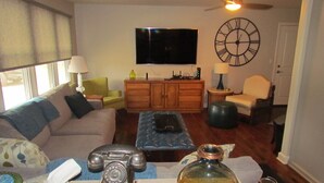 Una sala de estar con un sofá, una mesa de centro, un televisor, un reloj y una chimenea.
