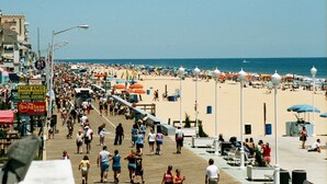 Ein belebter Promenadenweg mit Strandstühlen und Menschen.