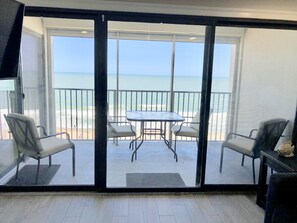 Enjoy the ocean view from your balcony with a glass door leading out to a seating area featuring a table and two chairs.