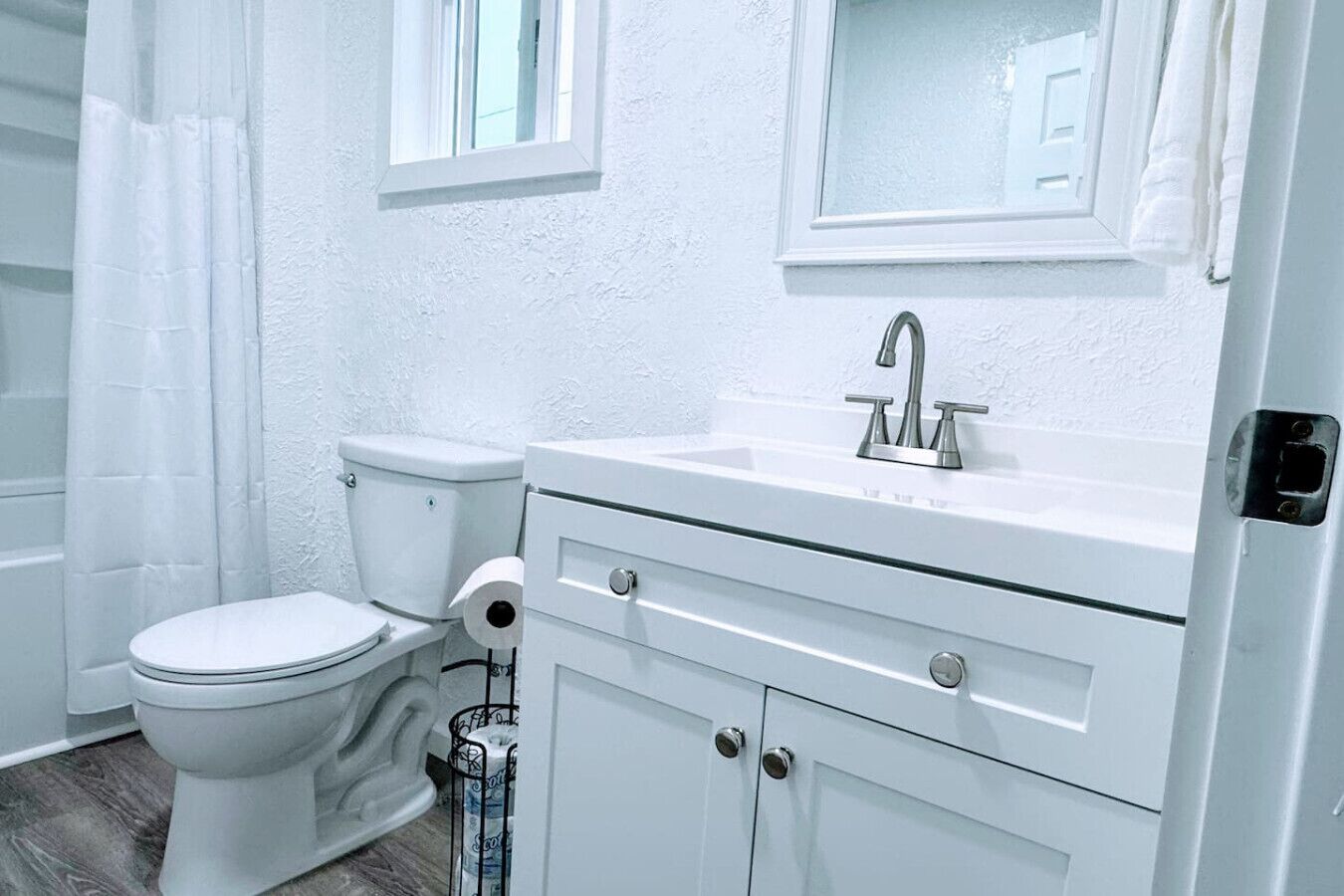 Une salle de bain avec des toilettes blanches, un lavabo doté d’un robinet moderne et un rideau de douche.