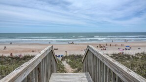 A wooden boardwalk leading to a sandy beach with people and umbrellas. - "Comes A Time" Oceanfront - Best Surf City location, walk to everything! (Surf City)