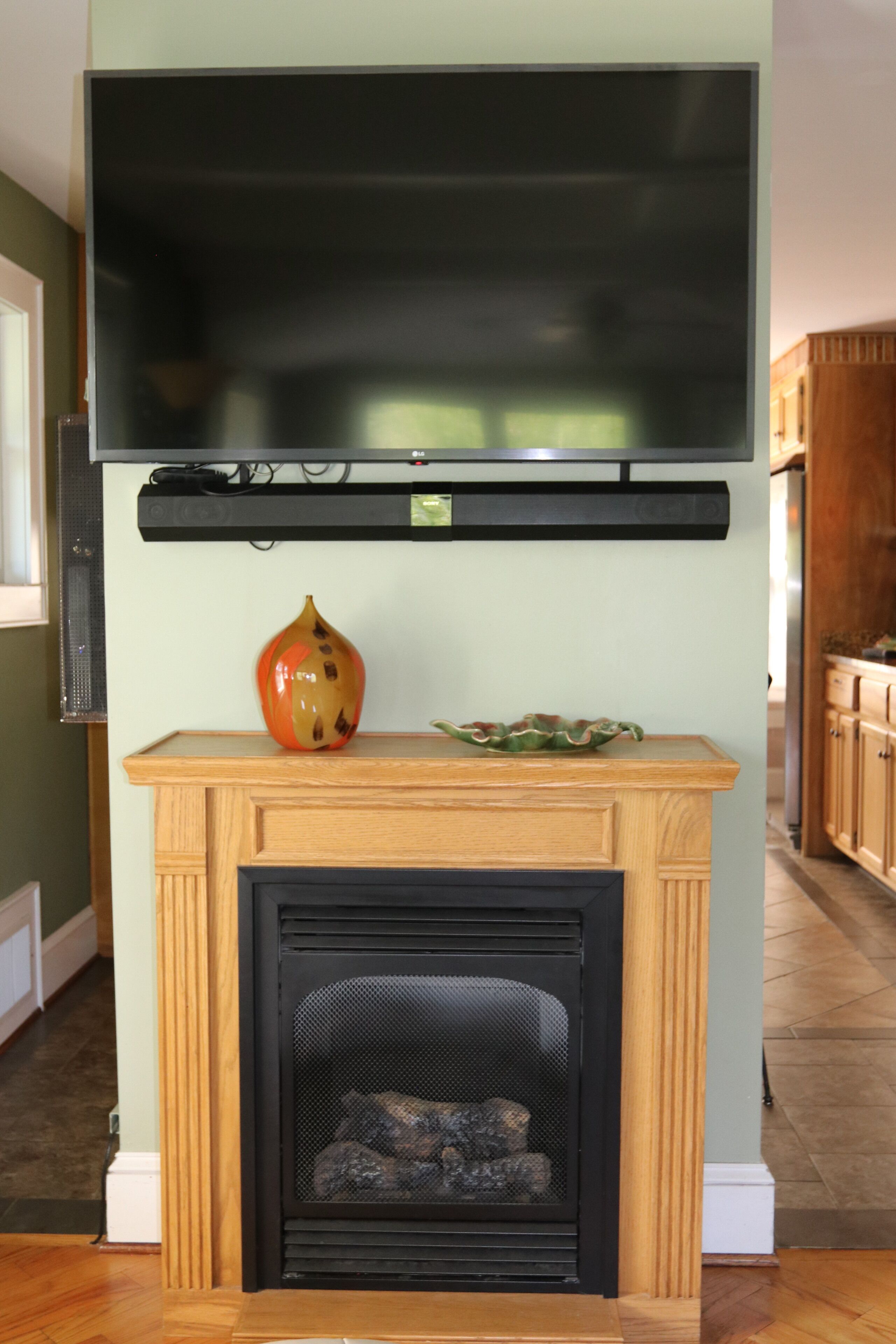Una chimenea con un televisor de pantalla plana montado encima, un jarrón decorativo y un cuenco sobre la repisa.
