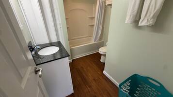 Une salle de bain équipée d’un lavabo, de toilettes, d’une douche et d’un panier à linge de couleur turquoise.