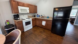 A kitchen with wooden cabinets, a white stove, a black refrigerator, and a microwave.