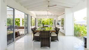 A modern dining area with a glass table, wicker chairs, and a ceiling fan. - Luxurious villa with panoramic views and breathtaking private infinity pool !!! (Tamarindo)