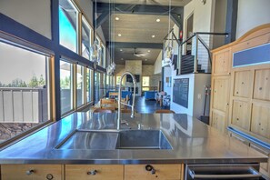 A modern kitchen with stainless steel countertops, wooden cabinets, and a view of the outdoors.