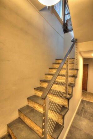 Un escalier au design moderne, doté d’une rampe en métal et de marches en bois.