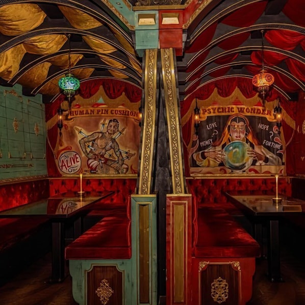 A bar with a mural of a muscular figure holding swords, a sign reading 'PSYCHIC WONDER,' and a green neon sign.