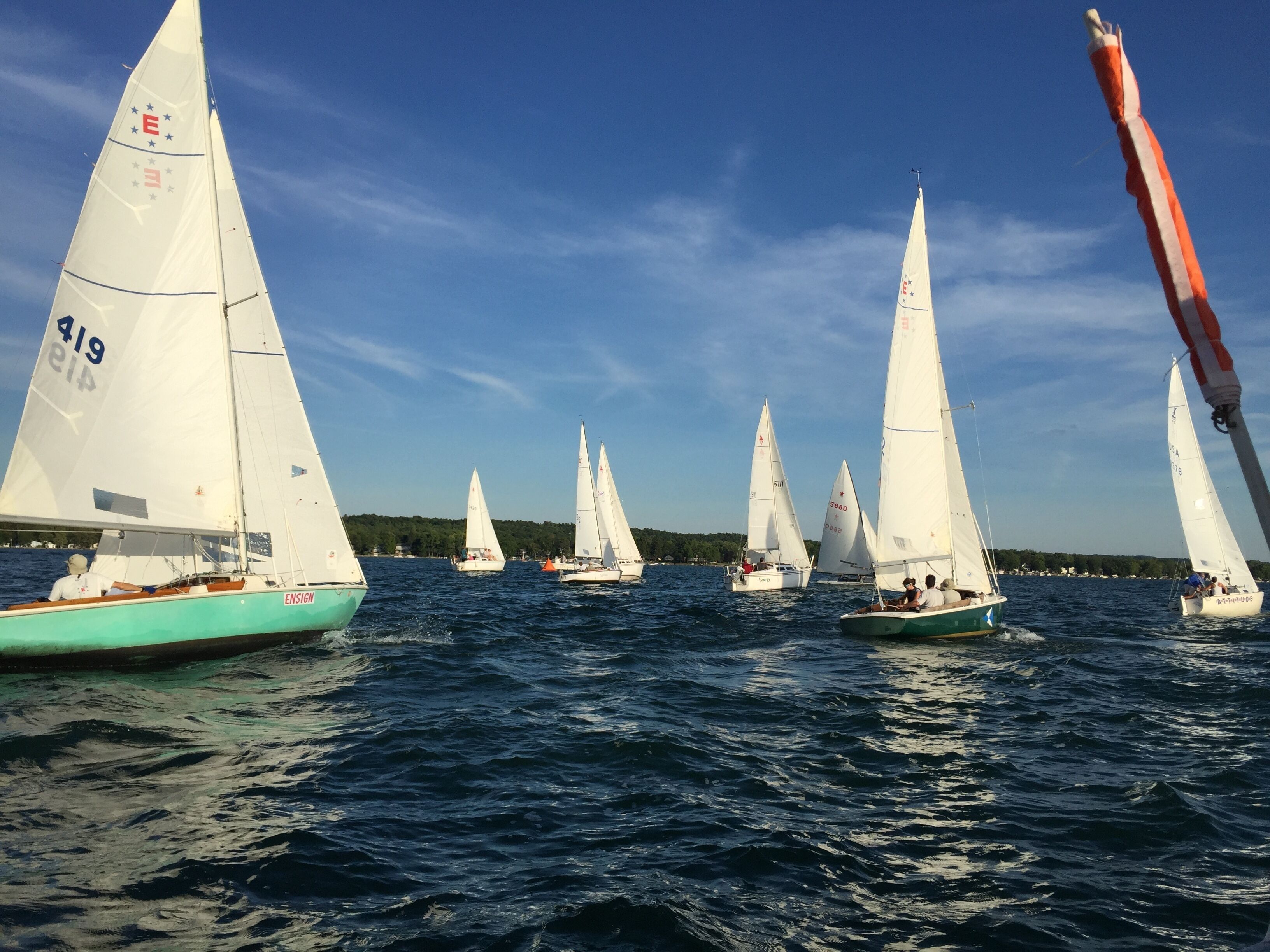 A fleet of sailboats on a body of water with a clear sky.
