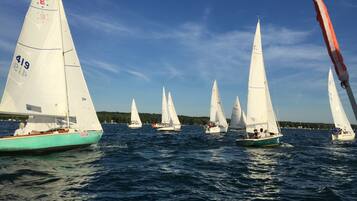 A fleet of sailboats on a body of water with a clear sky.