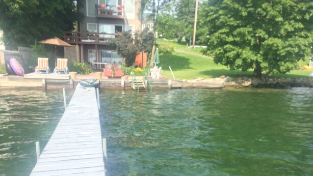 A wooden dock extending into a body of water, with a building and greenery in the background. - Lakeside fling! Same day bookings accepted with a VRBO reservation. Terms apply (Canandaigua)