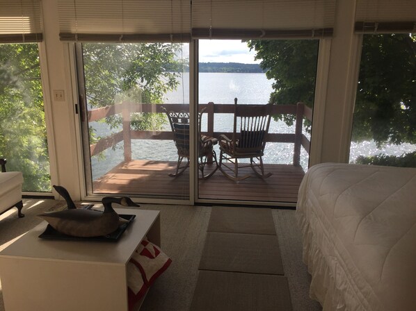 A bedroom with a view of a lake through a sliding glass door.