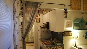 A compact kitchen with a refrigerator, microwave, and sink. A small window with blinds is visible, and a decorative birdhouse hangs on the wall. - Studio, Steps to Beach/Broadwalk Pool and Free Parking. Beach Terrace Building (Hollywood)