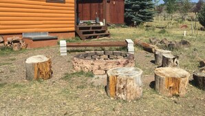A log cabin with a porch, a fire pit, and a wooden barn in the background. - Get Out Of The Heat And Enjoy The Mountain Air,  Catch Trophy Trout, Relax (panguitch)