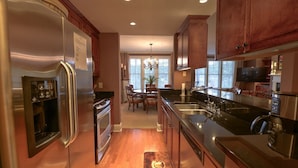 A kitchen with stainless steel appliances, wooden cabinets, a dining area with a chandelier, and a large window providing natural light. - WOW! 30% Off Until Oct. 1st | Walk to Ritz, Golf Front, 3 King Beds, Book Now (Greensboro)