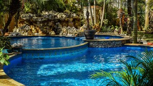 A pool with a waterfall feature, surrounded by tropical plants and a stone wall. - Private Luxury Villa 15,000 sq ft,kid friendly, Maid, pvt.Chef,24 h security (Playa Del Carmen)