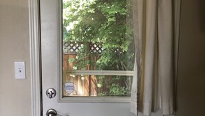 A white door with a window, a metal handle, and a doorbell. - Convenient & Cozy Cottage On Newport Near River, Downtown & Drake Park (Bend)