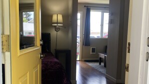 An open door leading into a room with a bed, a lamp, and a view of a balcony. - Convenient & Cozy Cottage On Newport Near River, Downtown & Drake Park (Bend)