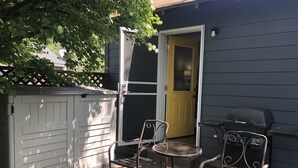 A patio with a grill, a small table, and two chairs. - Convenient & Cozy Cottage On Newport Near River, Downtown & Drake Park (Bend)