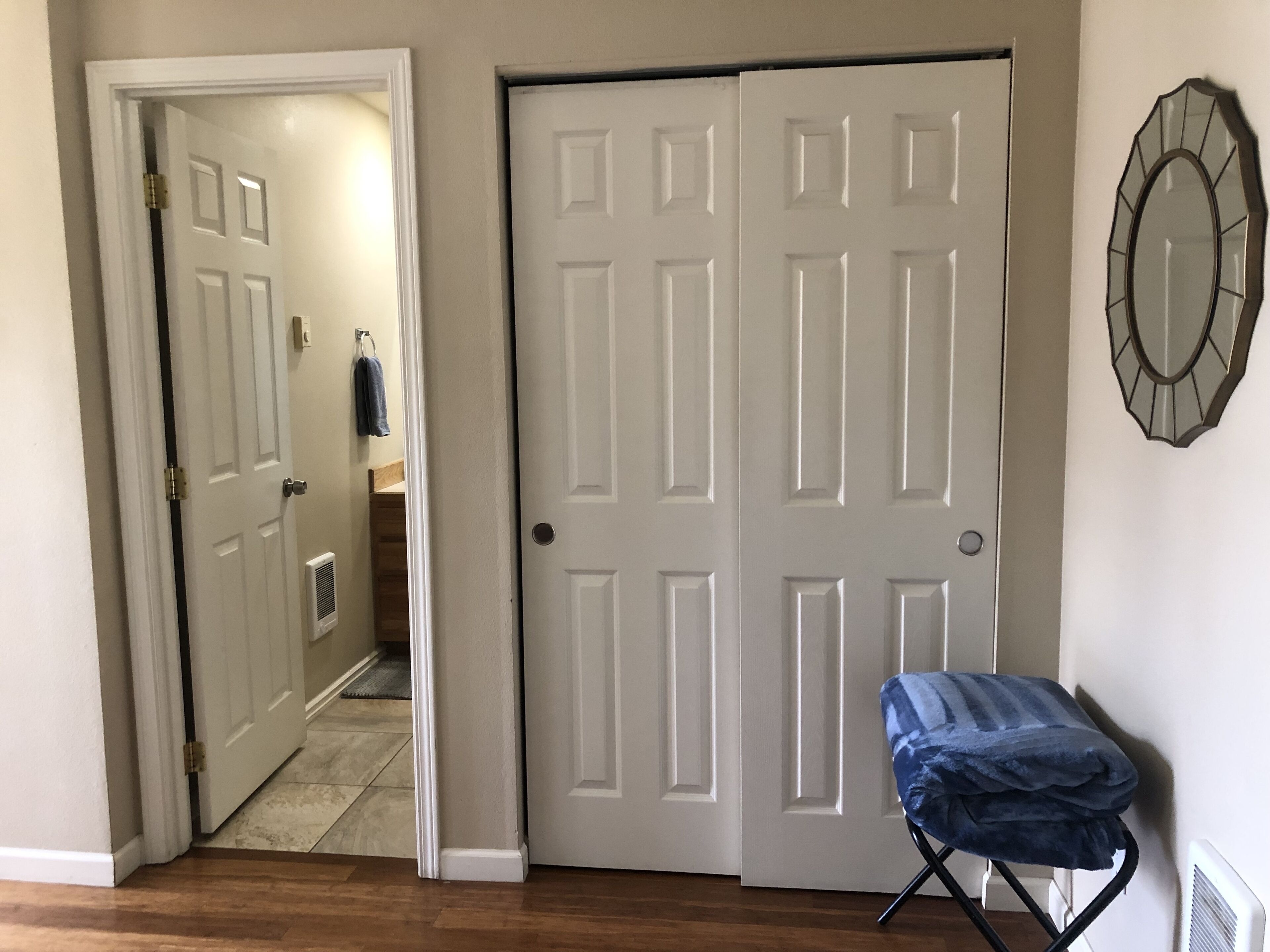 Una habitación con la puerta cerrada, un radiador y una toalla azul sobre una tabla de planchar.