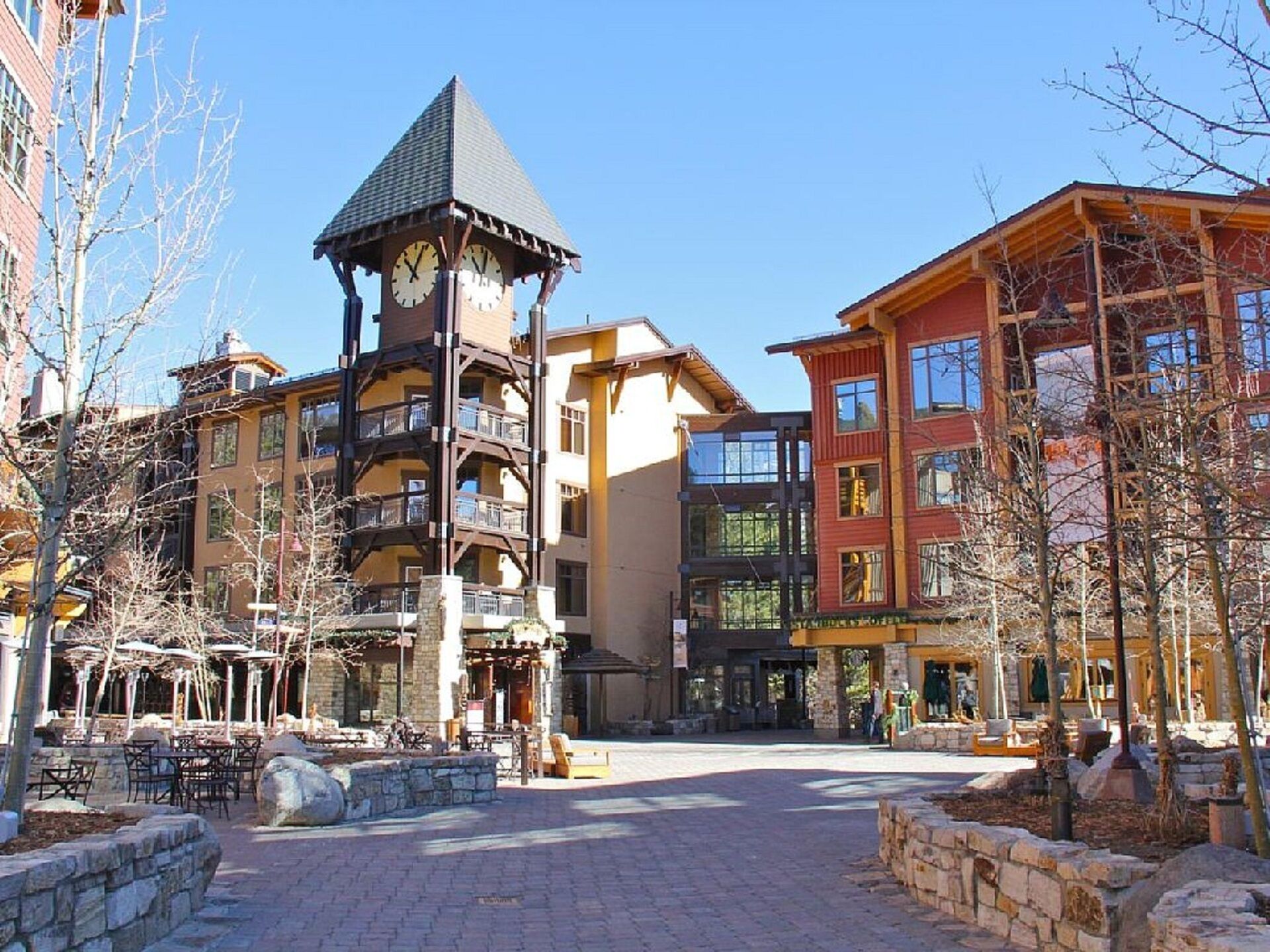 A building with a clock tower, multiple balconies, and a central courtyard with outdoor seating.