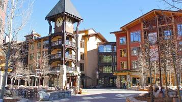 A building with a clock tower, multiple balconies, and a central courtyard with outdoor seating.
