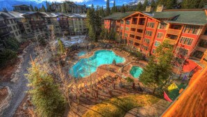 Un complexe hôtelier doté d’une grande piscine, entourée d’immeubles et d’arbres.