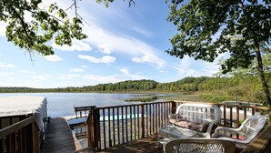 A wooden deck with wicker furniture overlooking a lake.