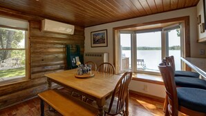 A wooden cabin interior with a dining table, chairs, and a bench.
