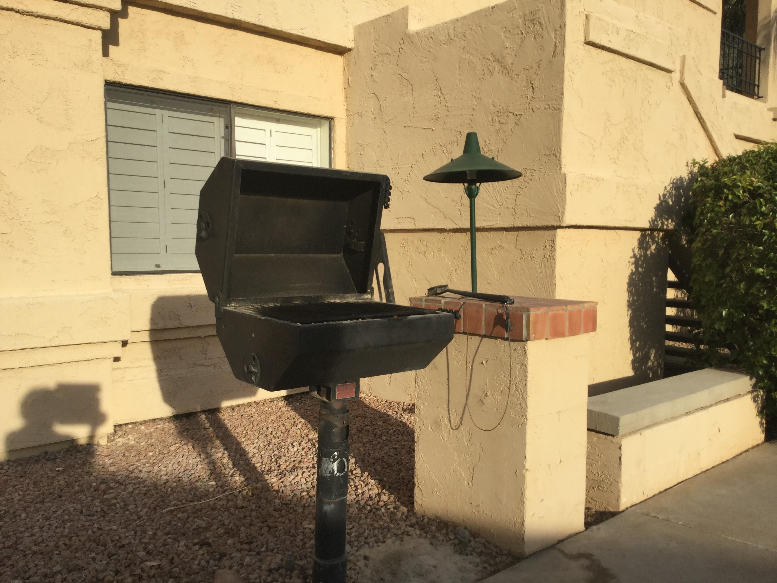 Una parrilla exterior con chimenea, una jardinera de ladrillo y un farol verde.