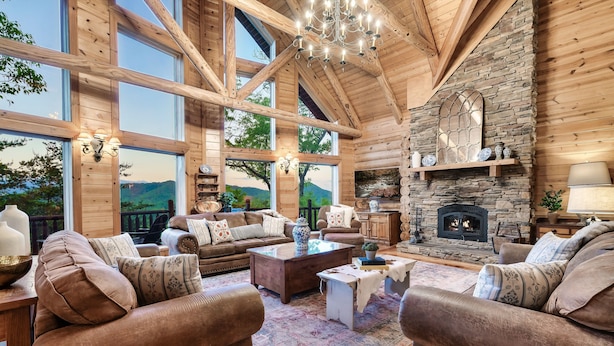 A spacious living room with large windows, a stone fireplace, and wooden beams. - Curated, One of a kind 7,000 sqft. Lodge, VIEWS & Pool (Sevierville)