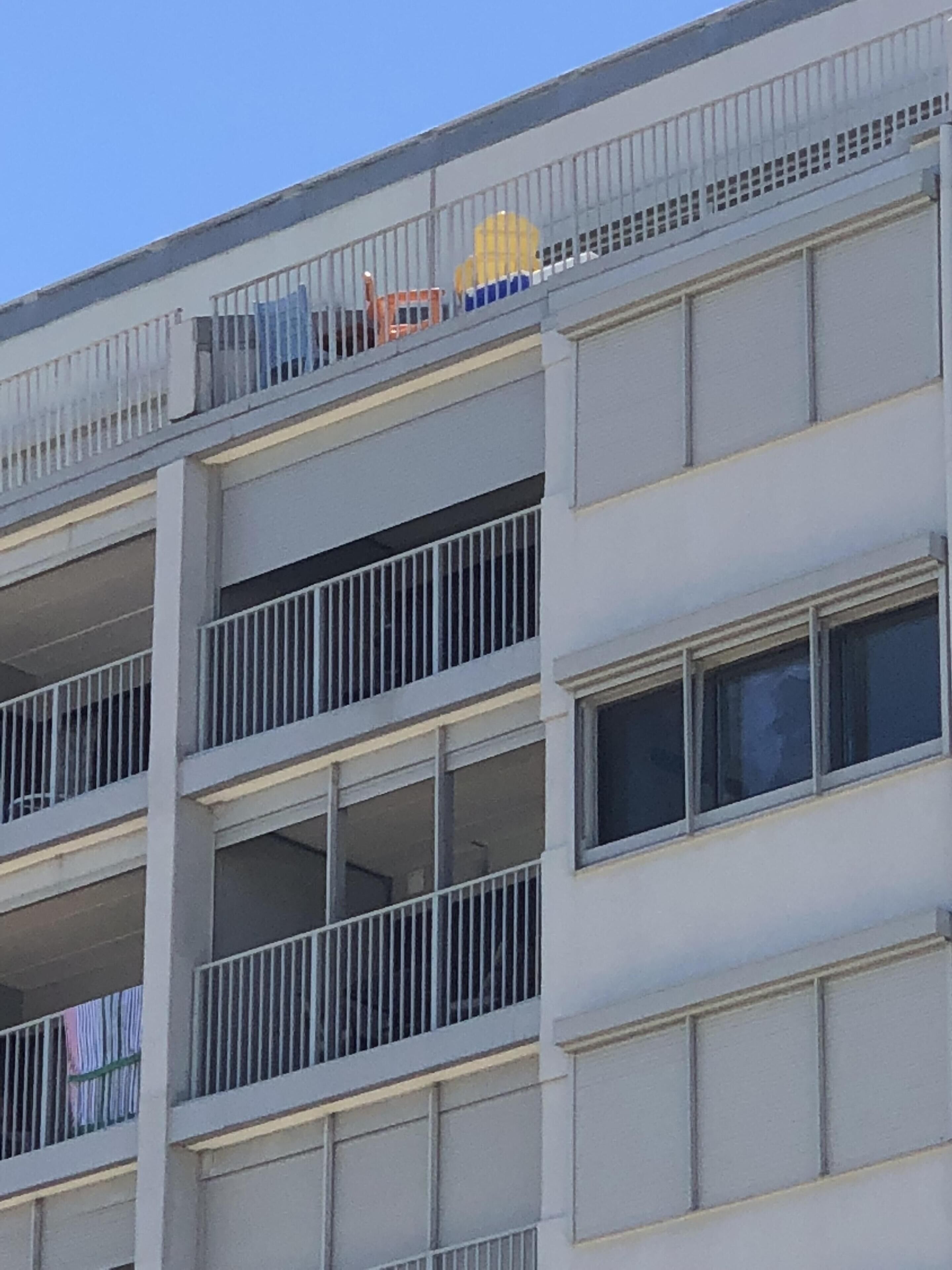 A multi-story building with balconies and large windows.