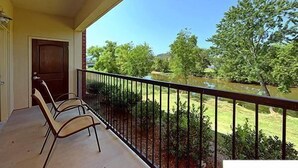 A balcony with a view of a pond and trees.