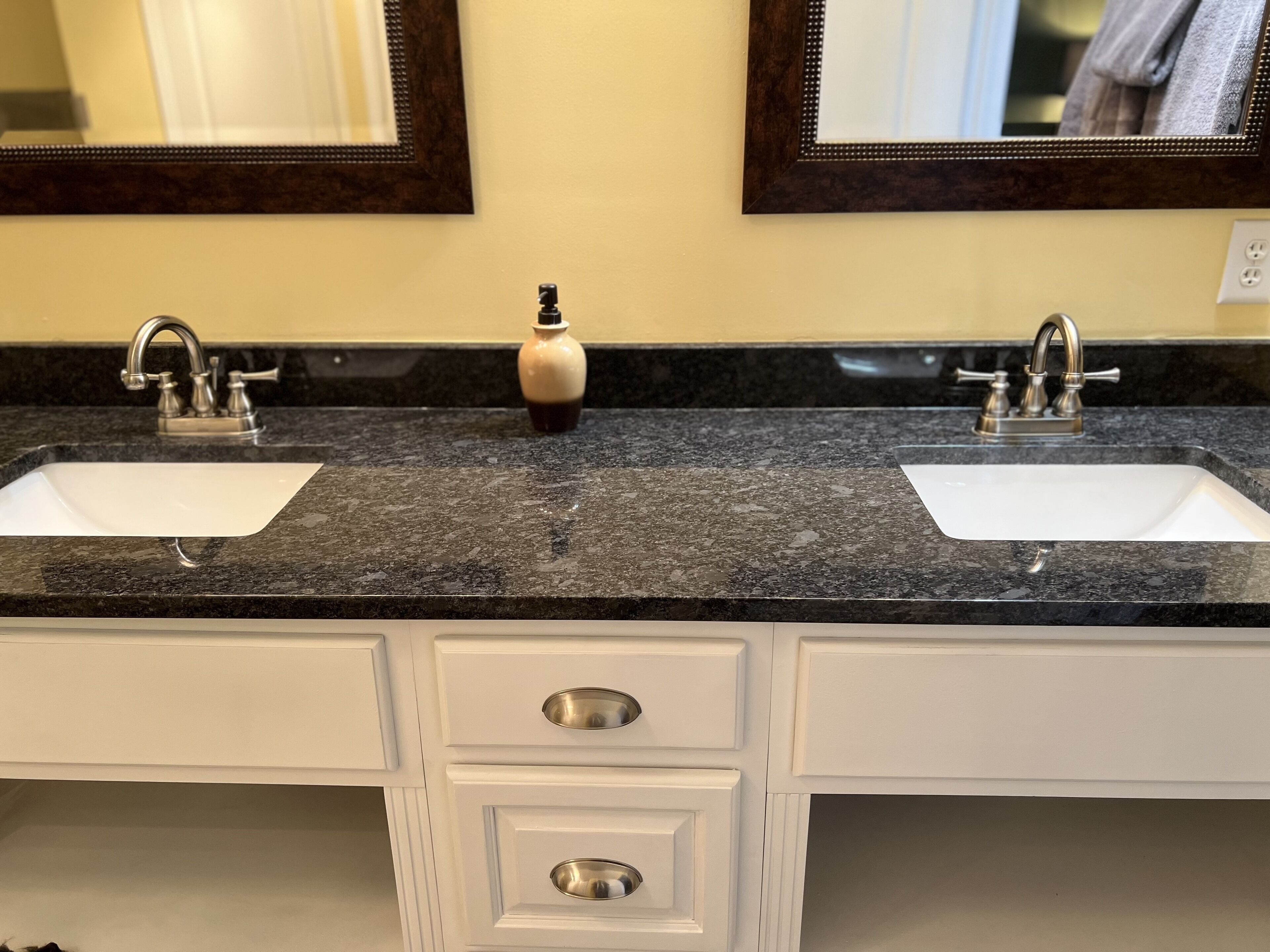 A bathroom with two sinks, a mirror, and a small bottle on the countertop.