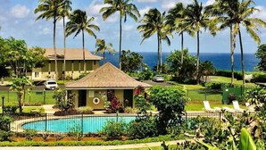 A hotel with a swimming pool, palm trees, and a view of the ocean. - The Dream View Vacation - OCEAN FRONT -  (Princeville)