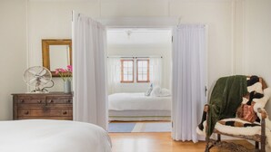 A bedroom with a wooden dresser, a chair with a blanket, a bed, and a mirror.