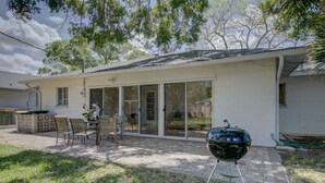 A house with a patio, a barbecue grill, and a covered outdoor seating area. - Charming Sarasota Home • Near Beaches & Downtown, 3bed, 2 bath. (Sarasota)