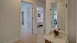 A hallway with a bed, a mirror, and a small table with flowers. - Charming Sarasota Home • Near Beaches & Downtown, 3bed, 2 bath. (Sarasota)