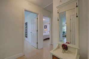 Enter a serene space with a large mirror above a console table, complemented by a carpeted floor and a door leading to another room.
