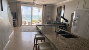 A kitchen with a granite countertop, a sink, and a dining area with a table and chairs. - DESIGN STUNNING LUXURY BEACH-HOUSE FULLY RENOVATED 5 Stars L (Nassau)
