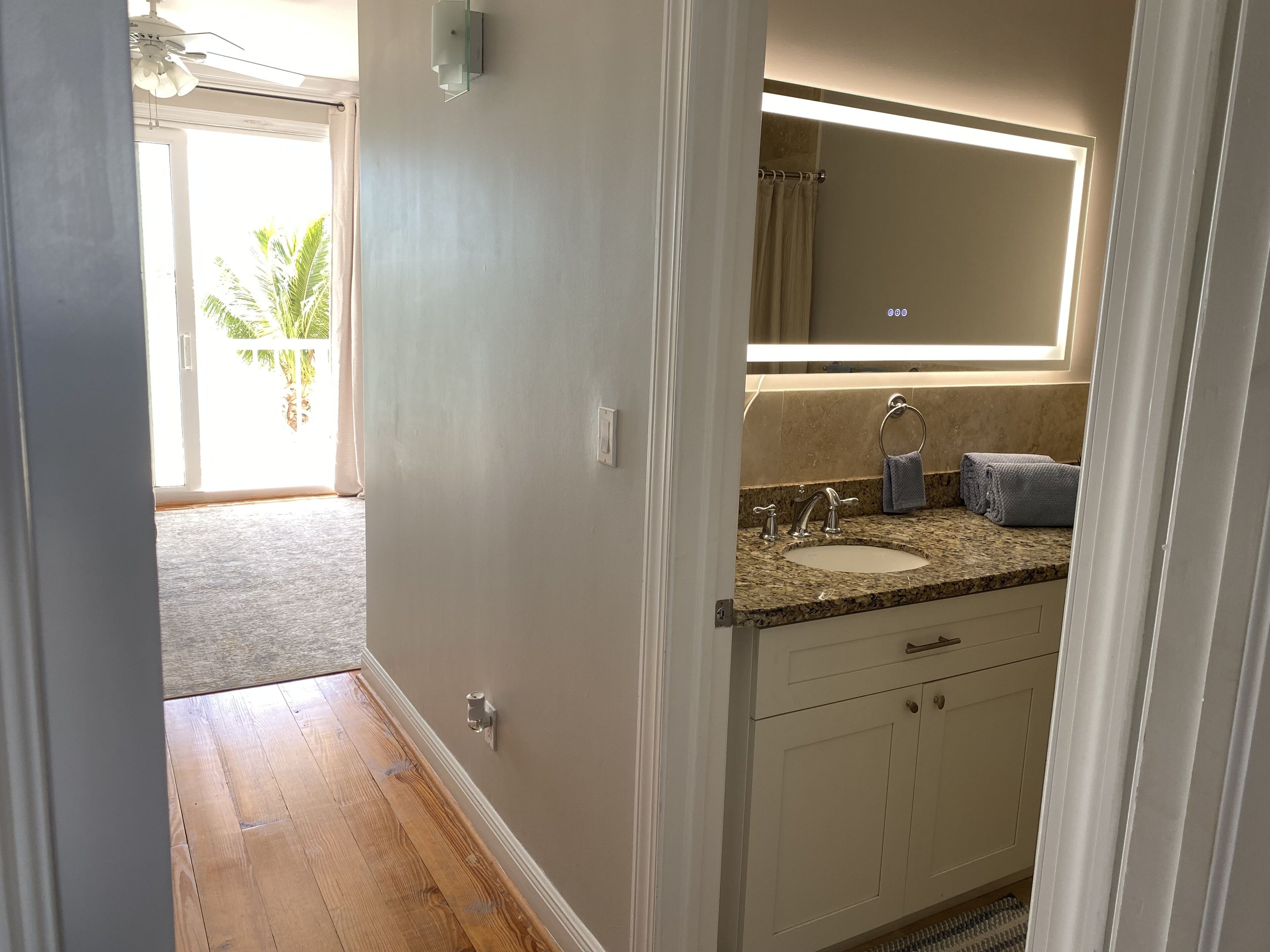 A bathroom with a granite countertop, a sink, a mirror, and a towel rack.