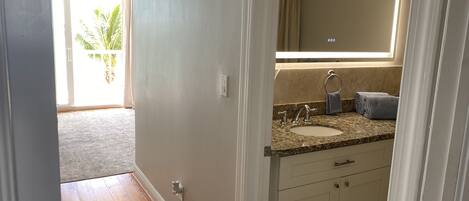 A bathroom with a granite countertop, a sink, a mirror, and a towel rack.